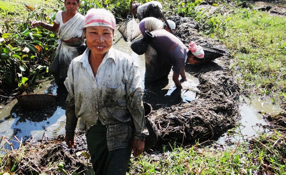 A Khasi tribal man shows his catch after fishing in a pond in