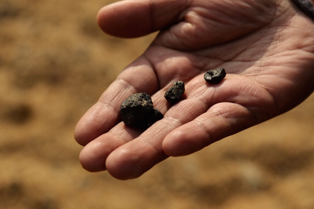 Writer and environmental activist, H. H. Mohrmen, shows pieces of coal picked up from the riverbank of Myntdu.